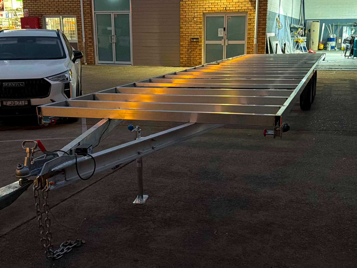 Aluminum Tiny House Trailer 6 meters by 2.4 meter duel Axel aluminum parked in a workshop.