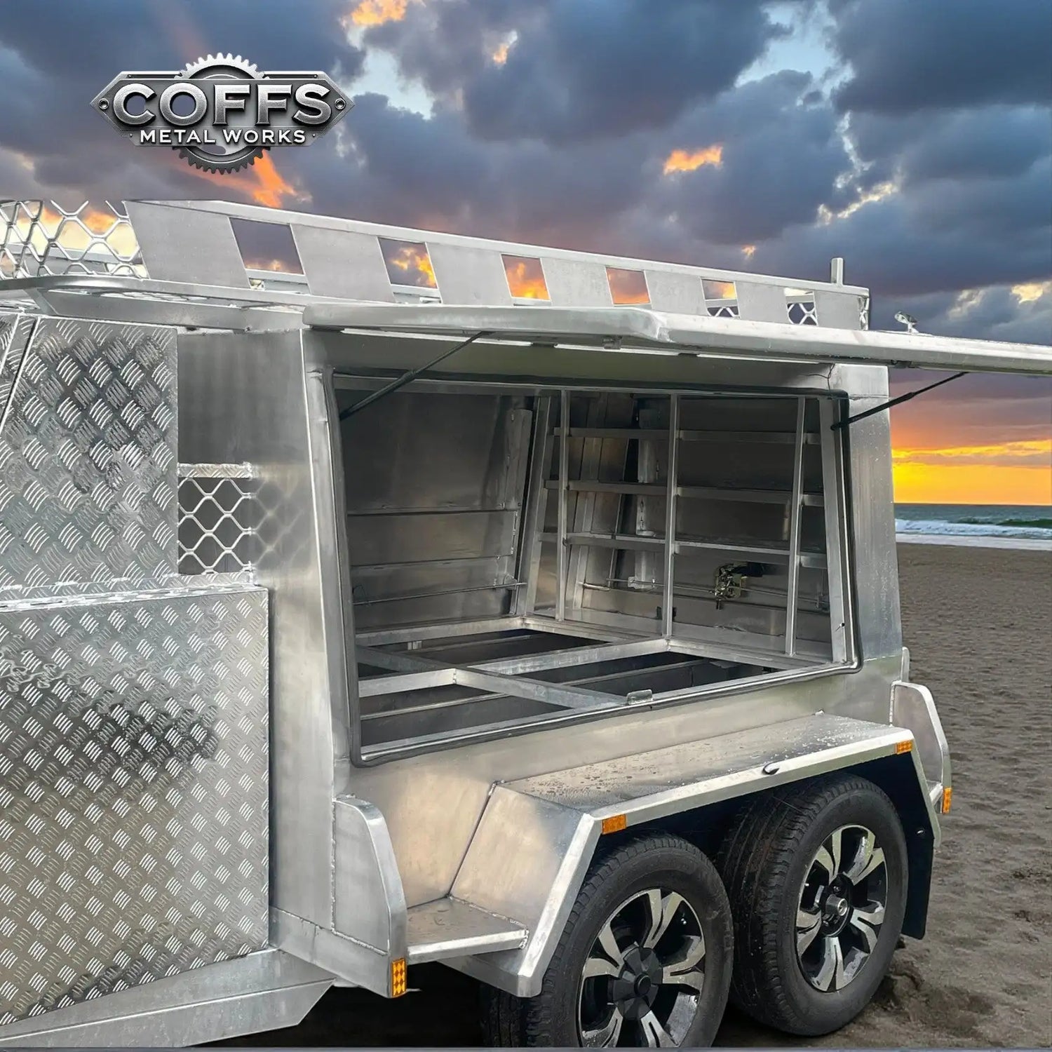 Silver aluminum utility trailer with diamond plate panels and a sliding side door, featuring an open storage compartment.
