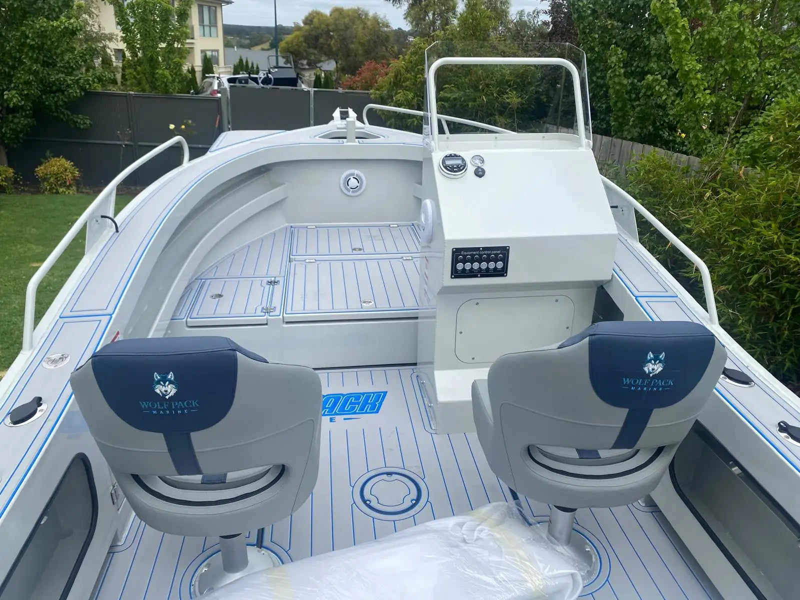 White and blue wolf pack marine boat with gray seats featuring a wolf logo, aluminum deck, and control panel.